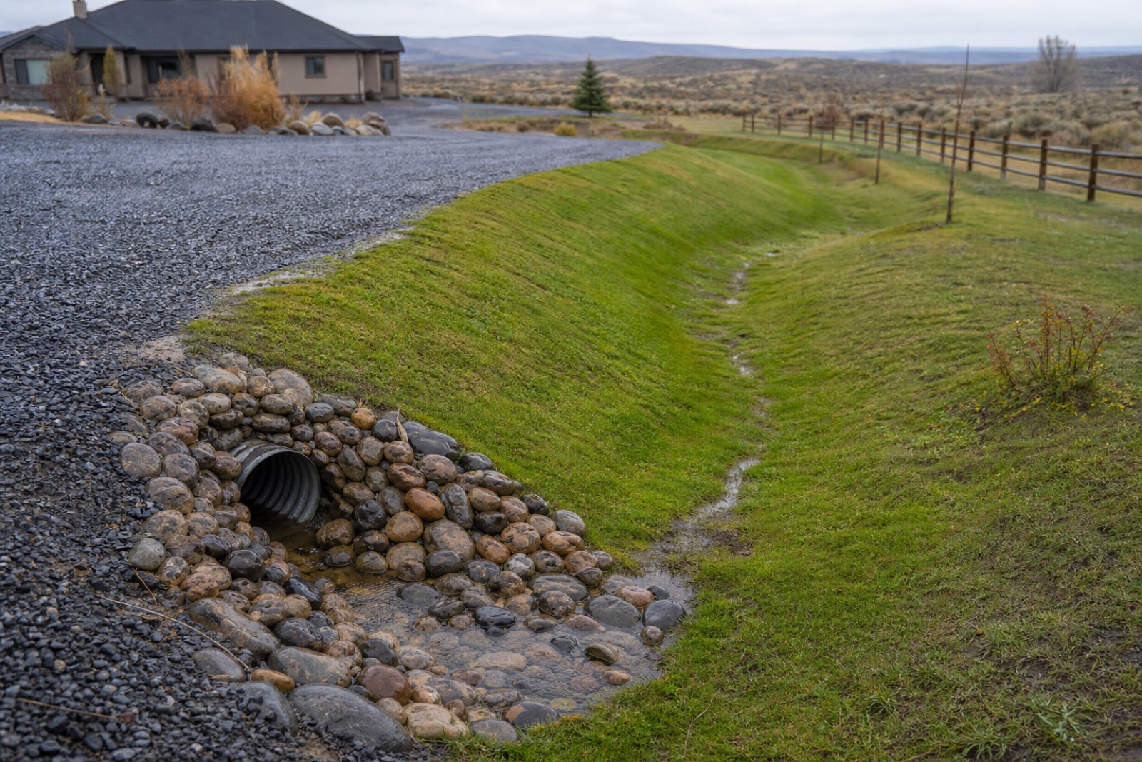Excavator shaping a drainage swale beside a Twin Falls area property