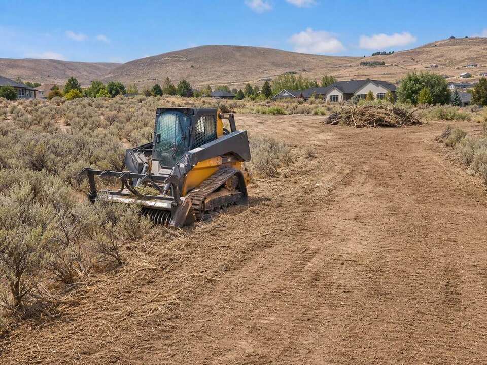 Excavator clearing brush and debris from a Twin Falls area property